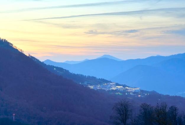 Le montagne del Caucaso al tramonto un villaggio nelle luci notturne su un pendio di montagna Rosa Khutor