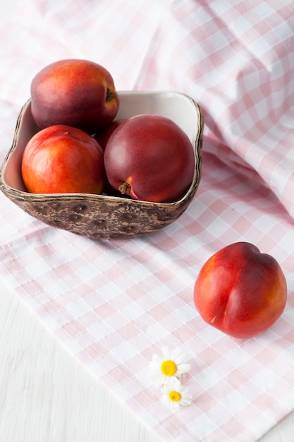 Le nettarine mature succose si trovano in un piatto fatto a mano sulla tovaglia