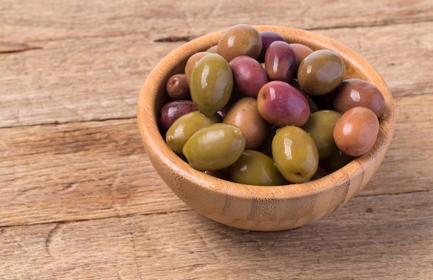 Le olive verdi in una ciotola su fondo in legno.