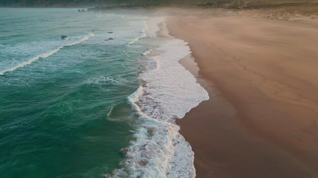 Le onde dell'acqua del mare schiumano la sabbia da vicino le onde tempestose dell'oceano lavano la spiaggia sabbiosa