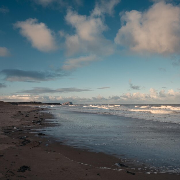 Le onde della spiaggia e le nuvole alla luce del giorno Lime Tree Walk Beach e Bass Rock Scozia Regno Unito