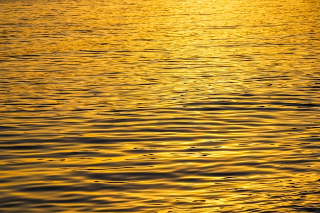 Le onde dorate del mare nel bagliore del tramonto come sfondo di superficie vacanze estive concept