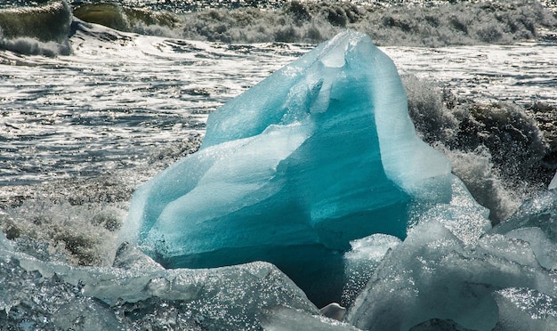 Le onde si infrangono e creano covoni di schiuma sui blocchi di ghiaccio respinti sulla spiaggia di Jokulsarlon