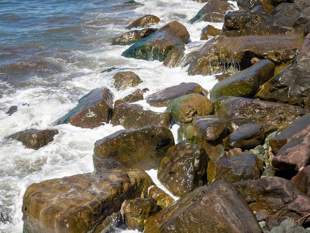 Le onde si infrangono su grandi rocce Costa rocciosa e onda Costa potente Schiuma di mare L'eccitazione del mare Enormi rocce costiere