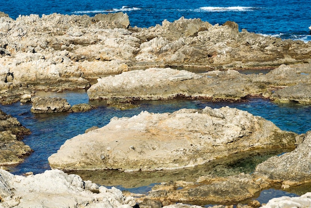 Le onde si infrangono sulla spiaggia rocciosa formando spruzzi Onde e spruzzi sulla spiaggia