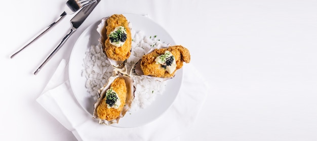 Le ostriche fritte nel grasso bollente che guarniscono con maionese e caviale sono servito in piatto bianco con sale marino