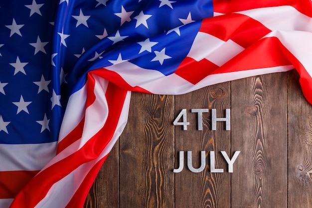 Le parole 4 luglio e bandiera usa sgualcita su uno sfondo di superficie in legno testurizzato piatto