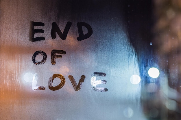 Le parole fine dell'amore scritte a mano sul vetro della finestra bagnata di notte