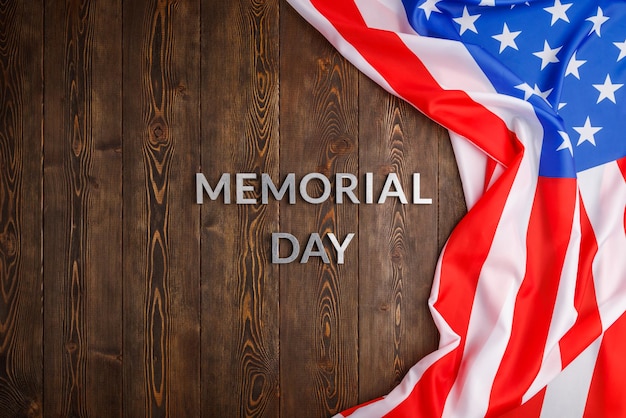 Le parole memorial day posate con lettere in metallo argentato su una superficie di legno con bandiera usa sgualcita