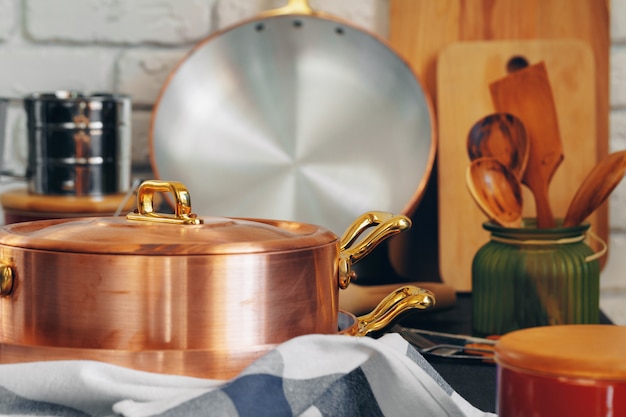 Le pentole di rame con gli utensili di legno della cucina si chiudono su