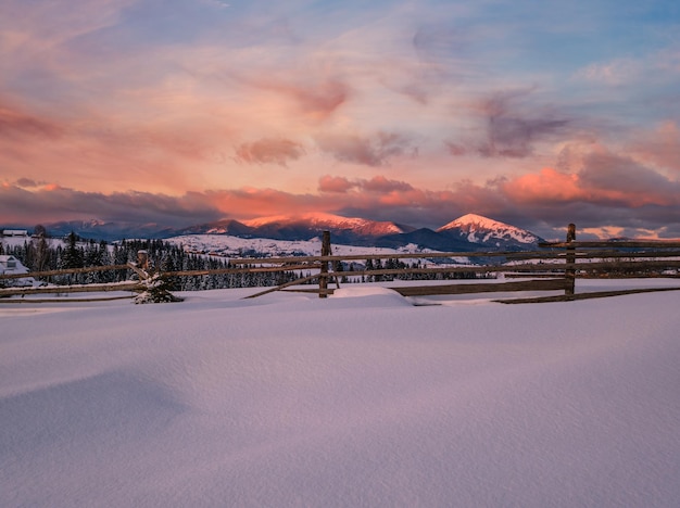 Le periferie del villaggio alpino all'ultimo tramonto, la luce del sole, le colline innevate d'inverno e gli abeti.