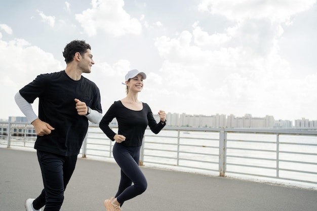 Le persone di fitness sono corridori felici e sani, un uomo e una donna si allenano insieme in abbigliamento sportivo