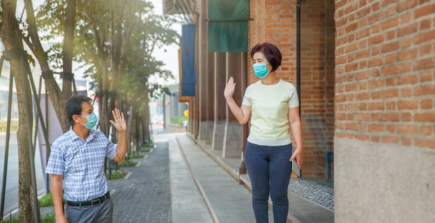 Le persone di mezza età asiatiche indossano maschera e mantengono le distanze sociali per evitare la diffusione di COVID-19