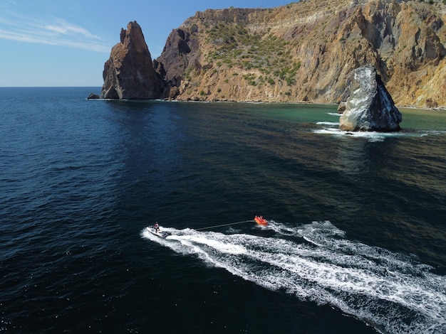 Le persone felici nuoteranno su un materasso ad aria dietro una moto d'acqua I turisti cavalcano il gonfiabile