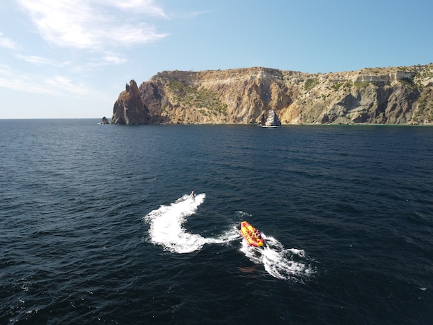 Le persone felici nuoteranno su un materasso ad aria dietro una moto d'acqua I turisti cavalcano il gonfiabile