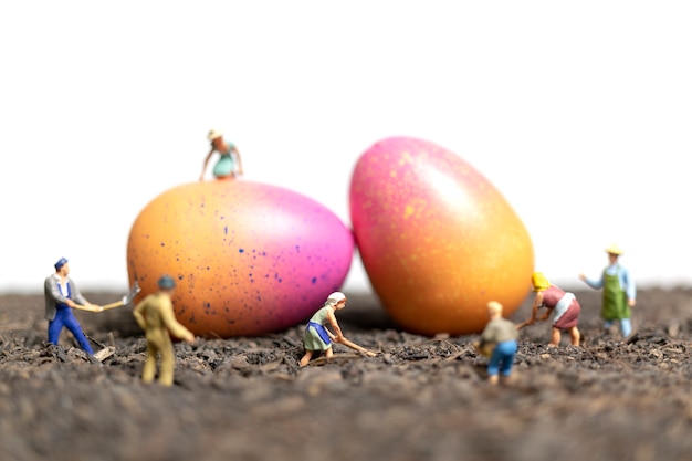 Le persone in miniatura lavorano alle uova di Pasqua per il giorno di Pasqua