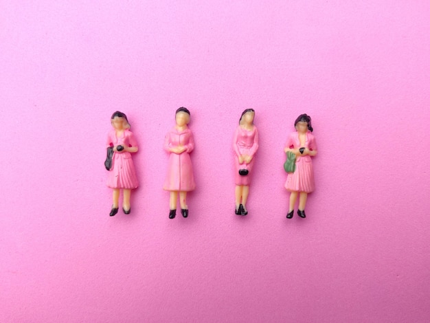 Le persone in miniatura sono disposte ordinatamente su uno sfondo rosa