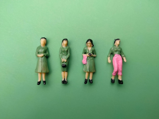 Le persone in miniatura sono disposte ordinatamente su uno sfondo verde