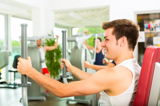 Le persone in palestra sportiva sulla macchina per il fitness