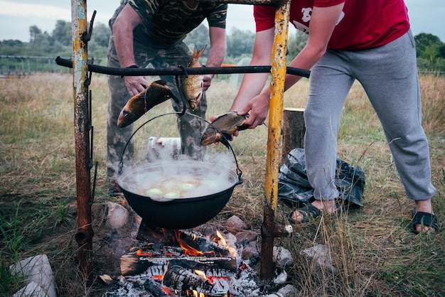Le persone nel campo in natura preparano la zuppa di pesce.