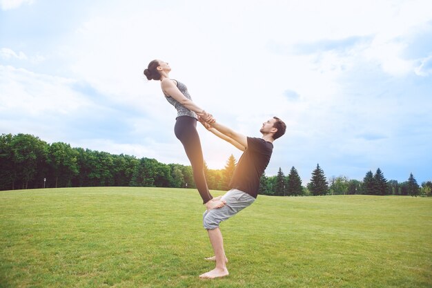 Le persone praticano l'acro yoga all'aperto con uno stile di vita sano