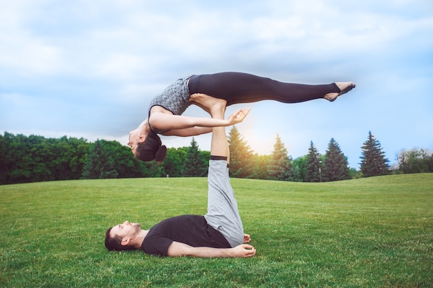 Le persone praticano l'acro yoga all'aperto con uno stile di vita sano