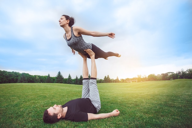 Le persone praticano l'acro yoga all'aperto con uno stile di vita sano