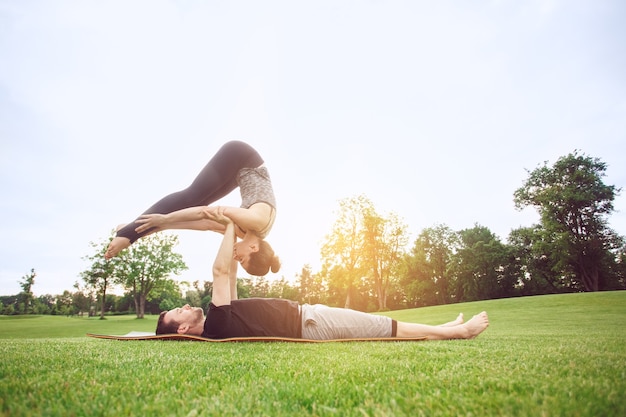 Le persone praticano l'acro yoga all'aperto con uno stile di vita sano