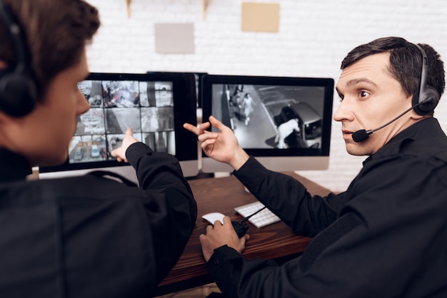 Le persone si siedono di fronte ai monitor nella stanza della sicurezza.