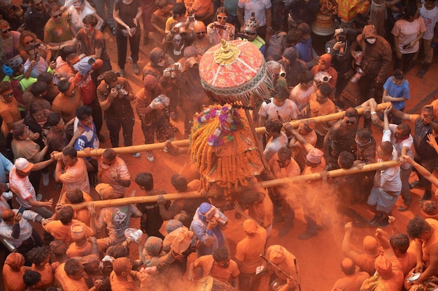 Le persone sono riunite in una festa con panni color arancio e un grande oggetto con sopra la parola "holi".