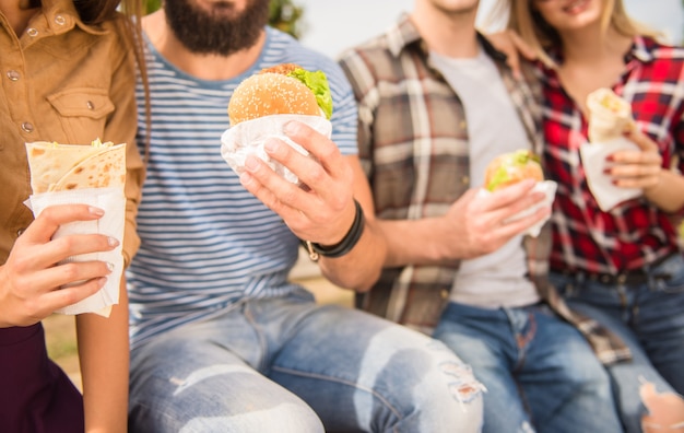 Le persone sono sedute nel parco e mangiano fast food.