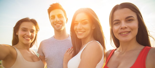 Le persone sorridenti fanno un selfie sullo sfondo del sole