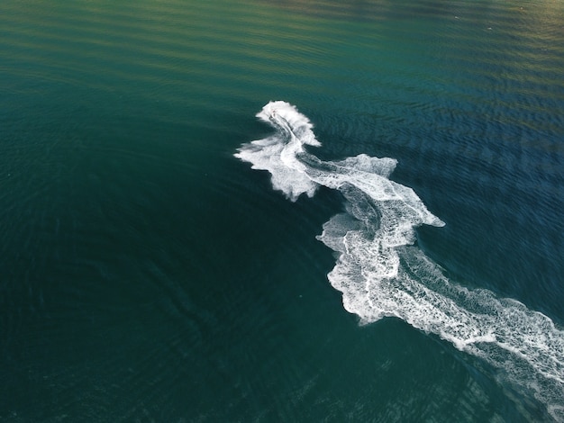 Le persone stanno giocando a una moto d'acqua nel mare lasciando impronte bianche astratte sulla parte superiore dell'antenna dell'acqua