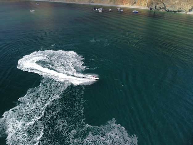 Le persone stanno giocando a una moto d'acqua nel mare lasciando impronte bianche astratte sulla parte superiore dell'antenna dell'acqua