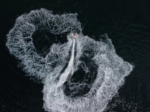 Le persone stanno giocando a una moto d'acqua nel mare lasciando impronte bianche astratte sulla parte superiore dell'antenna dell'acqua