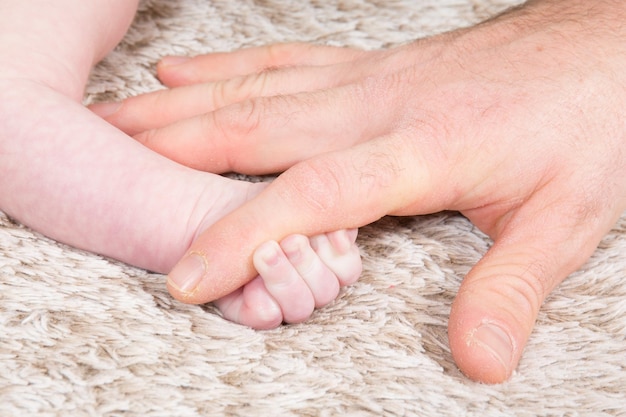 Le piccole dita del bambino afferrano la mano della mamma