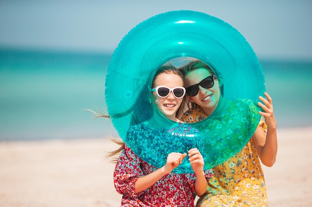 Le piccole ragazze divertenti e felici si divertono molto sulla spiaggia tropicale giocando insieme