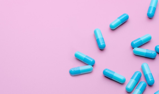 Le pillole blu della capsula antibiotica si sono sparse sull'industria farmaceutica del fondo rosa