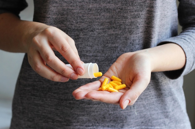 Le pillole mediche in mani femminili prendono gli additivi alimentari delle vitamine delle pillole