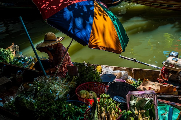 Le popolazioni locali vendono frutta, cibo e souvenir al mercato galleggiante famosa attrazione turistica in Thailandia
