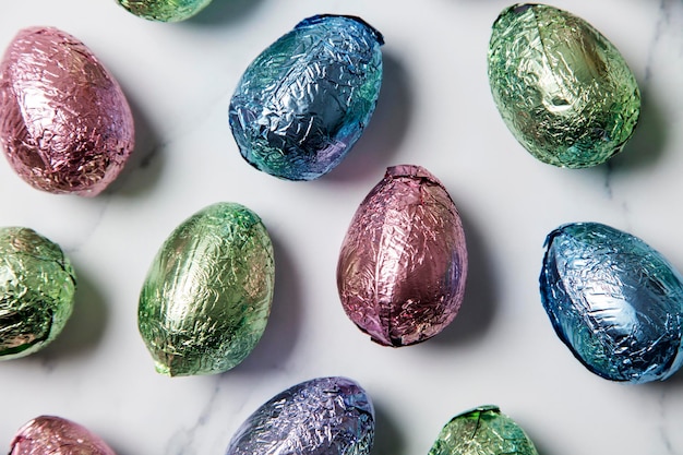 Le prelibatezze al cioccolato all'uovo di Pasqua si avvolgono in un foglio colorato lucido su uno sfondo di marmo