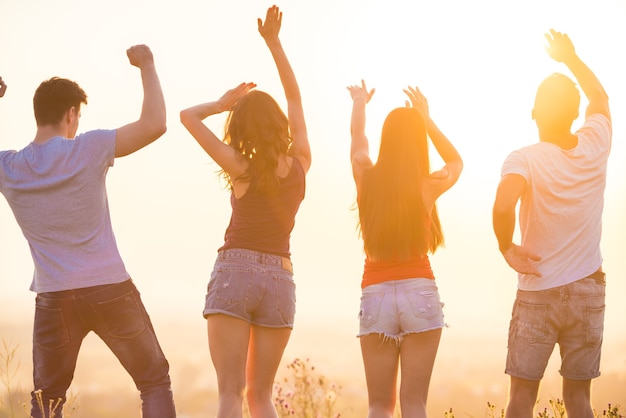 Le quattro persone che ballano sullo sfondo del tramonto