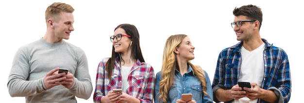 Le quattro persone felici con i telefoni stanno sullo sfondo del muro bianco