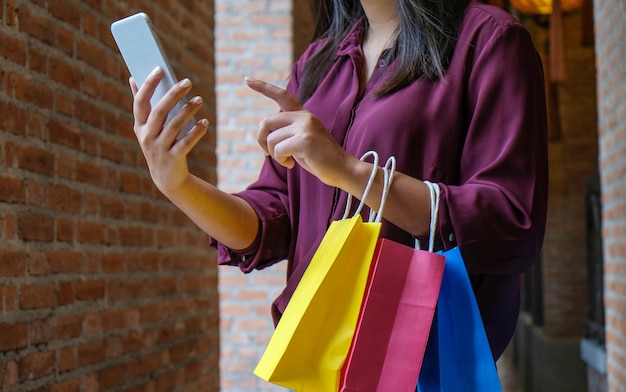 Le ragazze asiatiche che tengono il concetto di stile di vita di consumismo dei sacchetti della spesa di vendita nel centro commerciale signora turistica camminano nel centro commerciale con le borse della spesa