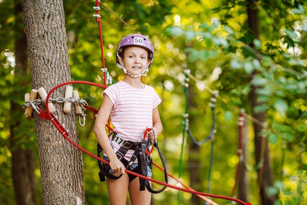 Le ragazze con attrezzatura da arrampicata in un parco avventura sono impegnate nell'arrampicata su roccia o superano ostacoli sulla strada a fune