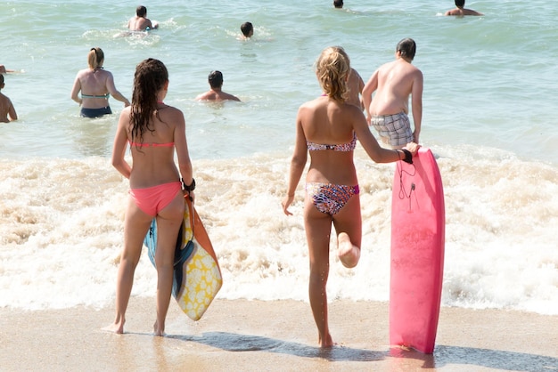 Le ragazze del surfista vanno alla spiaggia dell'acqua da dietro la vista