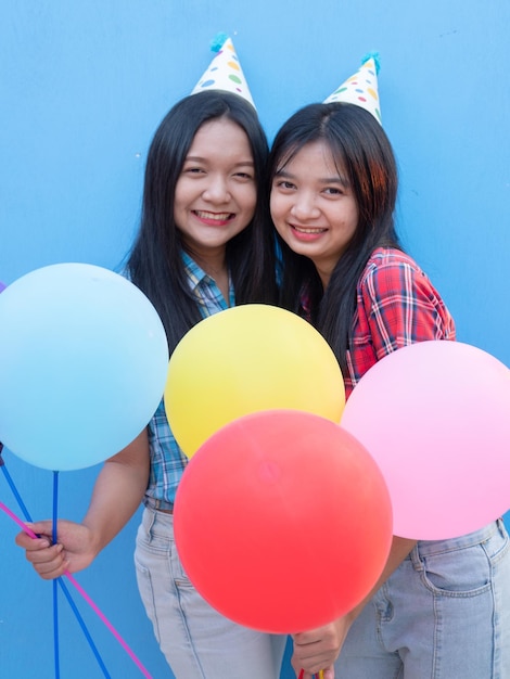Le ragazze felici si godono la festa con lo sfondo blu colorato del palloncino