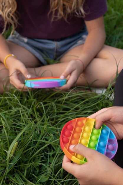 Le ragazze giocano con il popolare giocattolo pop-it in silicone colorato all'aperto sull'erba verde