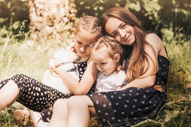 Le ragazze giocano nel parco con un coniglio bianco nel parco. Divertente attività primaverile per bambini. Tempo di Pasqua