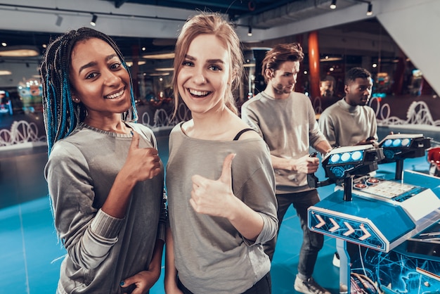 Le ragazze sono in posa in arcade rinunciare pollici.